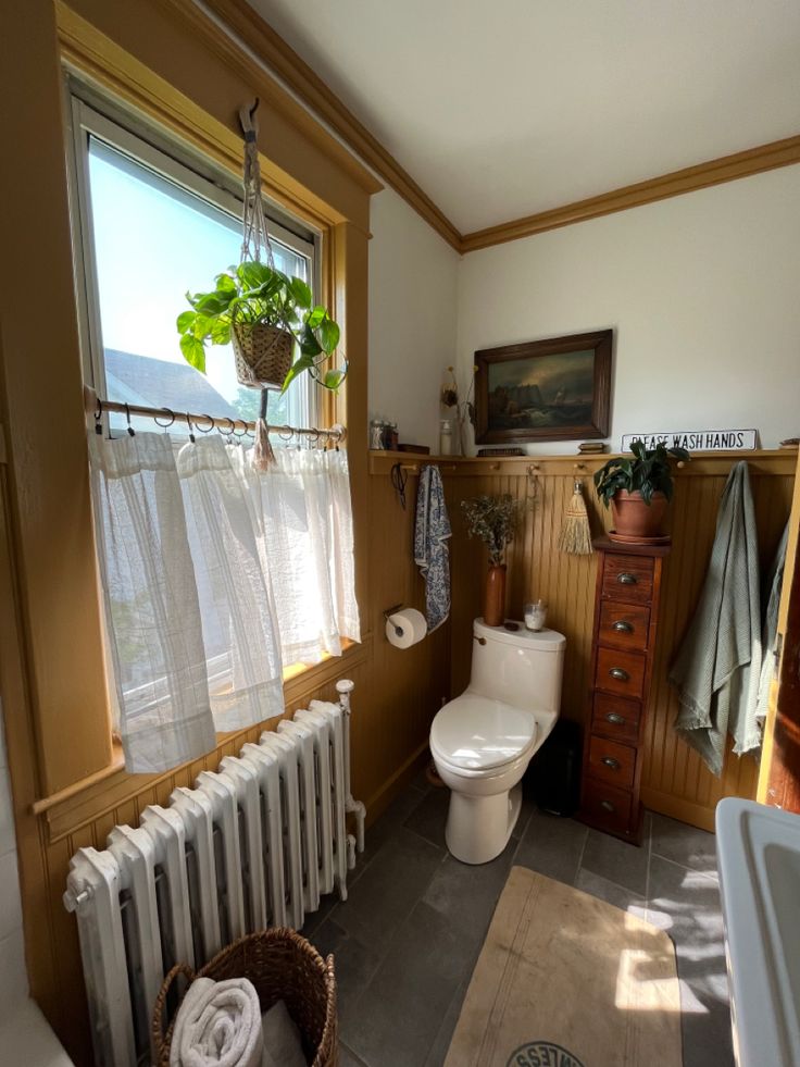 a bathroom with a white toilet sitting next to a radiator in front of a window