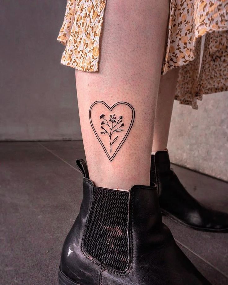 a woman's leg with a small heart and flowers tattoo on her left ankle