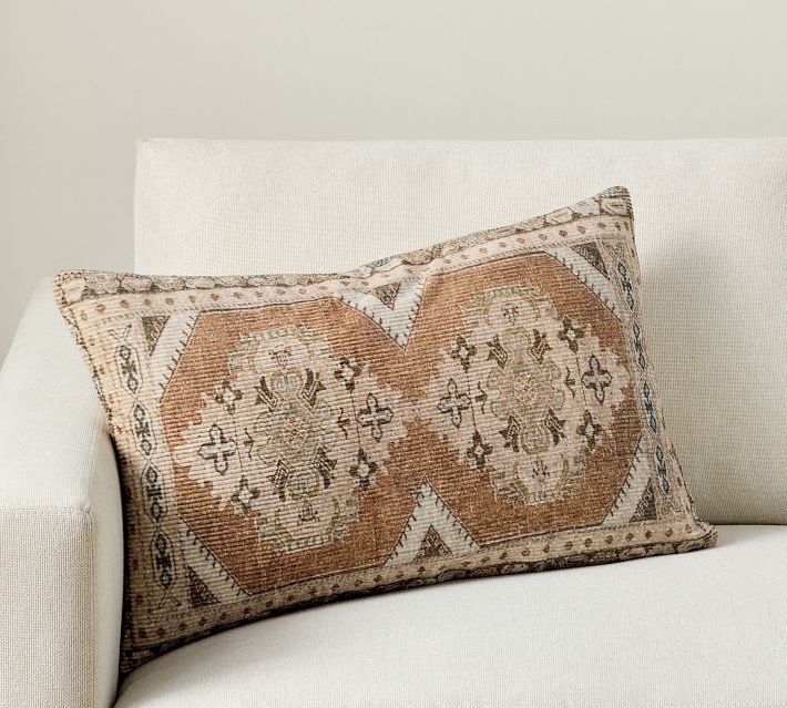 a white couch with a decorative pillow on it's back and the cushion is made out of fabric