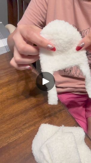 a woman holding a white stuffed animal on top of a wooden table