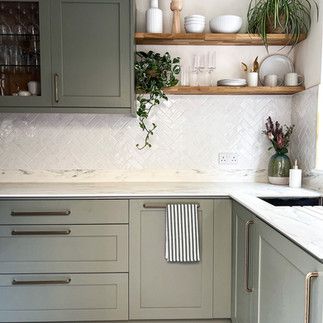 a kitchen with green cabinets and white counter tops