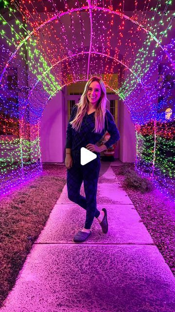 a woman running down a walkway covered in christmas lights