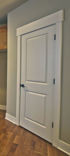 an empty room with white doors and wood flooring