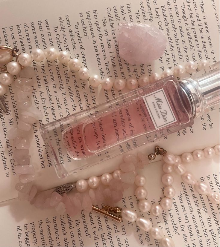 a bottle of perfume sitting on top of a table next to pearls and necklaces