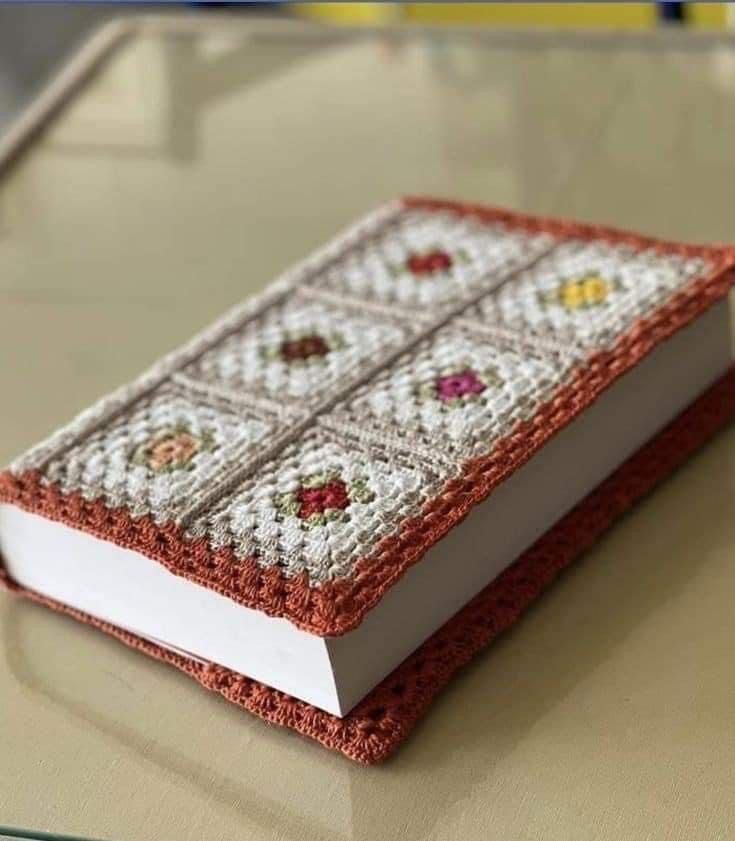 an open book sitting on top of a table covered in cross stitching and beads