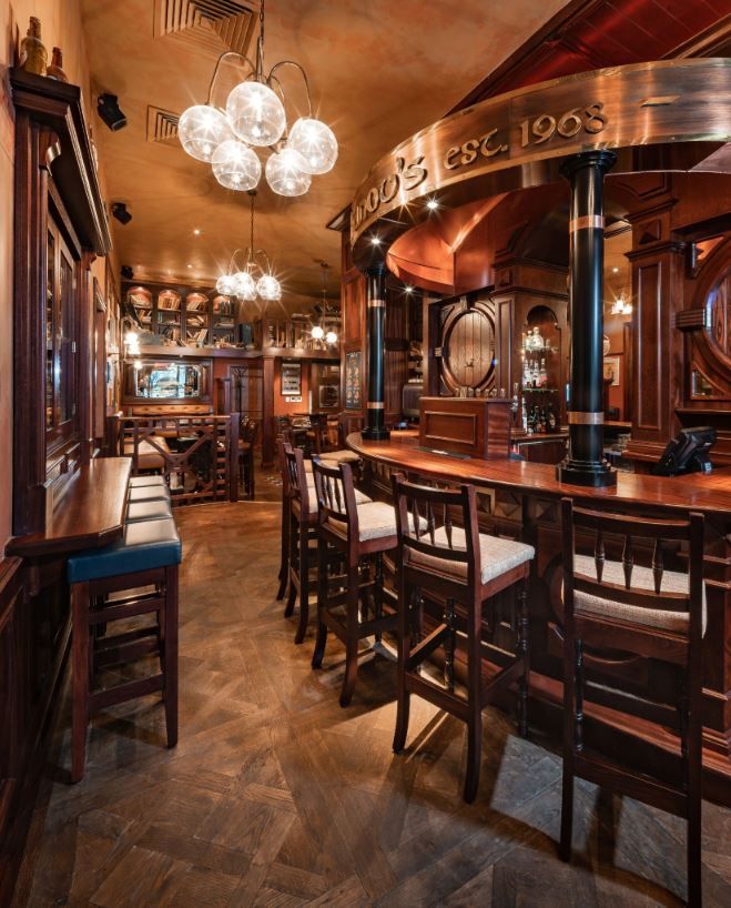 the interior of a restaurant with wooden tables and chairs, chandeliers and lights