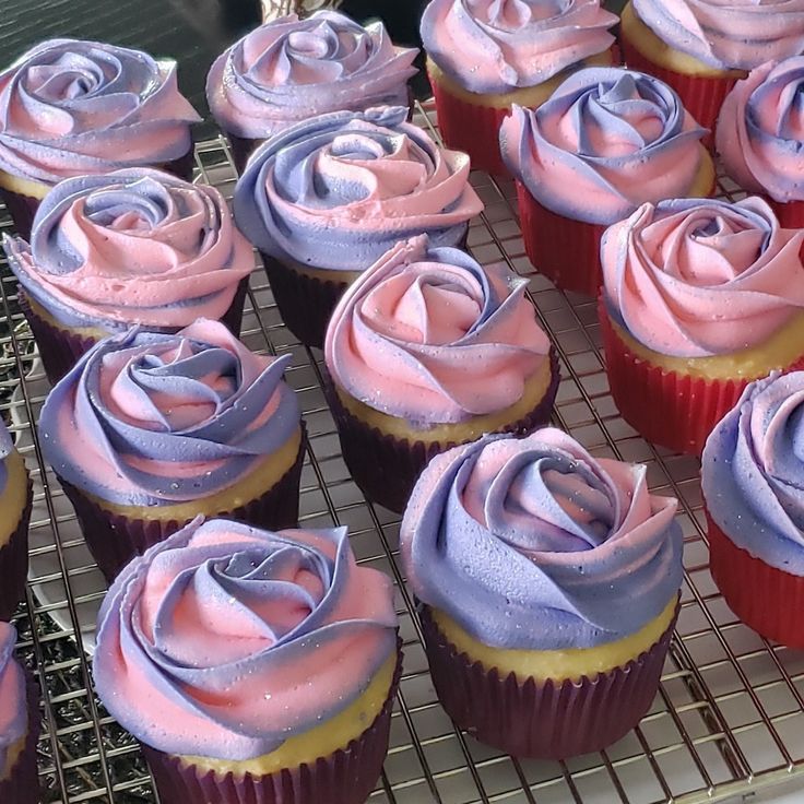 cupcakes with pink and purple frosting sitting on a cooling rack