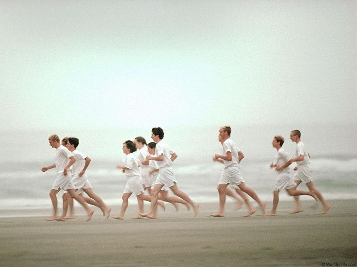 a group of people run along the beach in white clothes and head to toe down