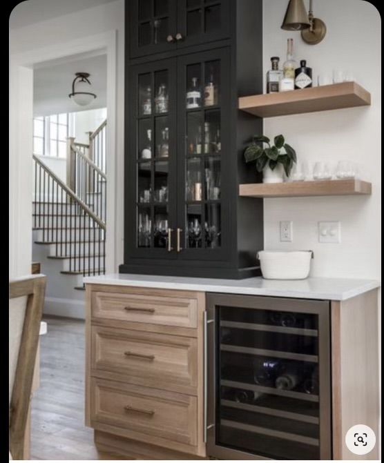 a kitchen with black cabinets and shelves filled with bottles, wine glasses and other items