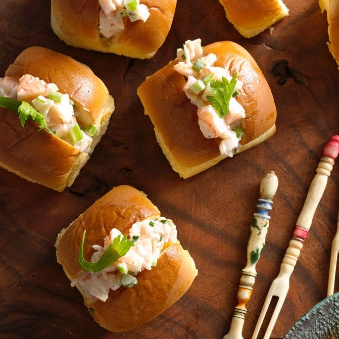 small rolls with crab salad on them sitting on a wooden table