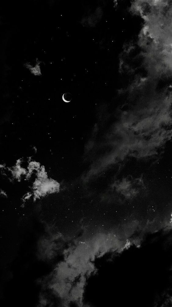 black and white photograph of the night sky with moon and stars in the clouds above