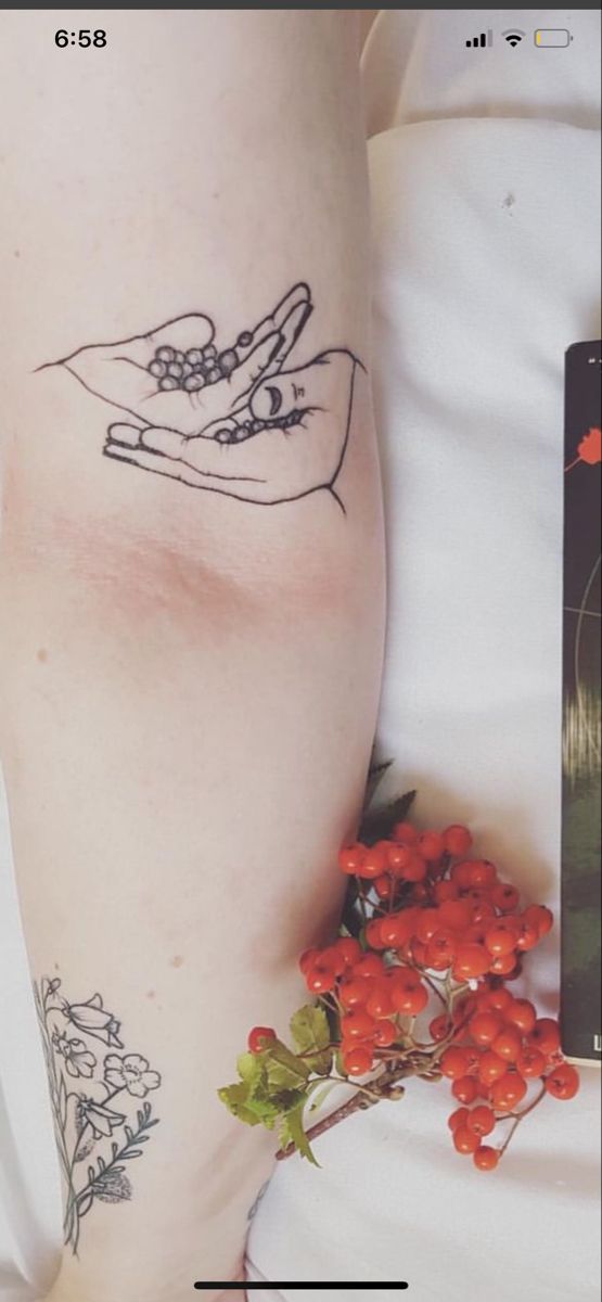 a woman's arm with tattoos on it and flowers in the background, next to a book