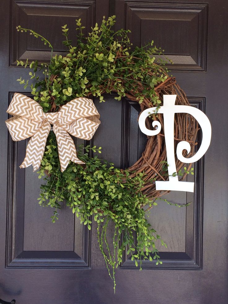 a wreath with the letter d on it and a bow hanging from it's front door