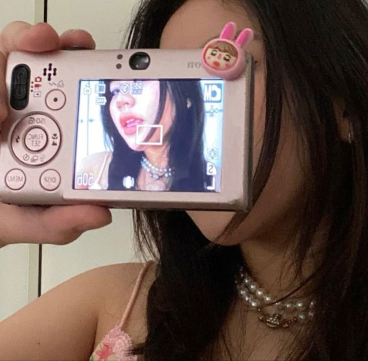 a woman taking a selfie with her cell phone in front of her face and holding it up to the camera