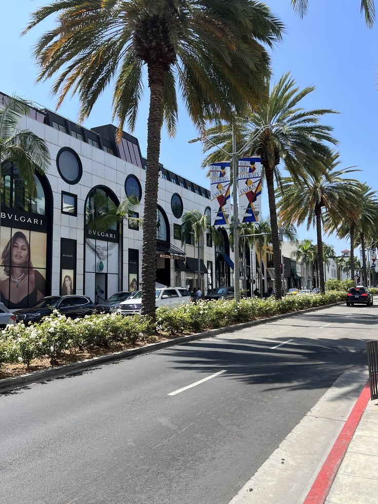 palm trees line the street in front of a building with an advertisement on it's side