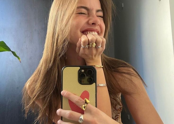 a woman taking a selfie with her cell phone in front of her face and smiling