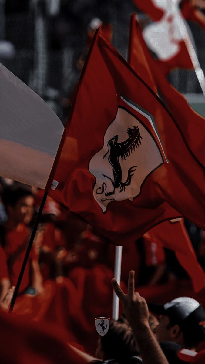 a group of people holding red flags and waving their hands in the air at an event