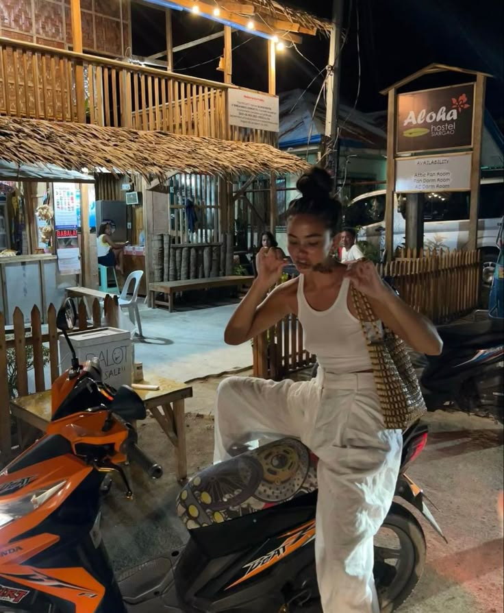 a woman standing on top of a motor scooter in front of a building