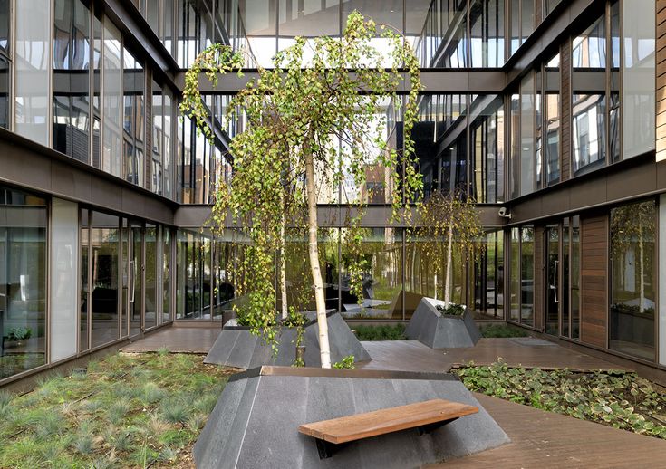 a bench sitting in the middle of a courtyard next to tall buildings with glass windows