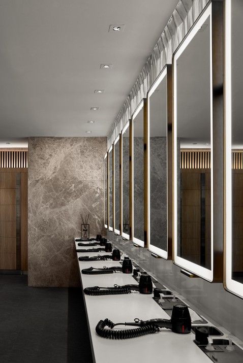 a long row of sinks in a bathroom with mirrors on the wall and lights above them