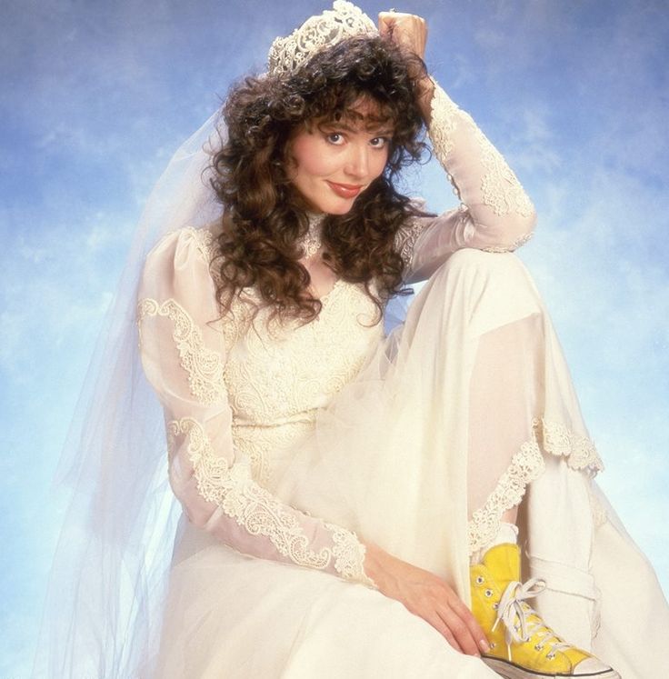 a woman in a white wedding dress sitting on the ground wearing yellow shoes and a tiara