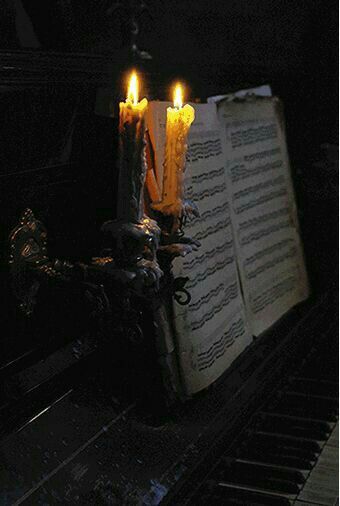 three candles are lit on top of an open book with music sheets in the background