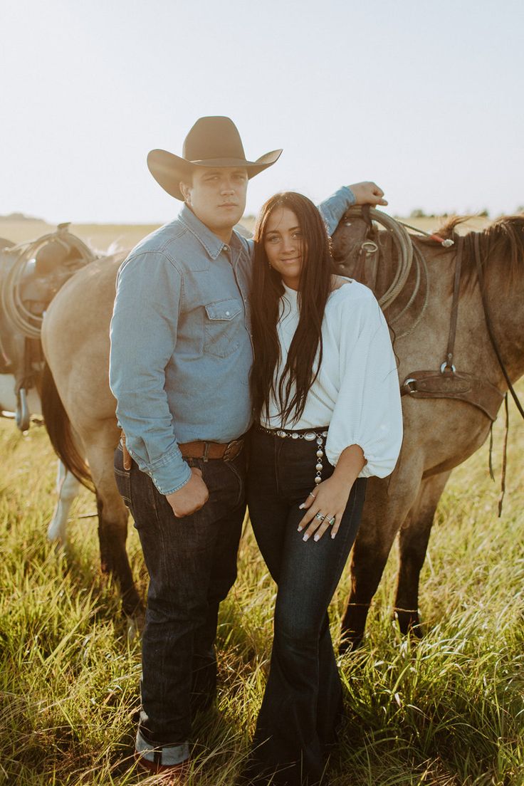 a man and woman standing next to each other in front of horses on a field