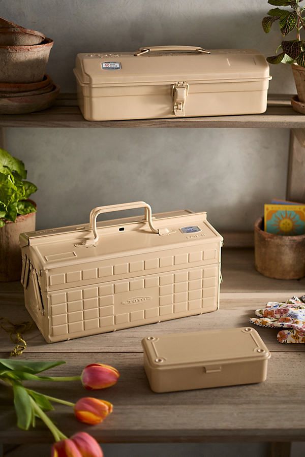 two tan suitcases sitting on top of a wooden table next to tulips