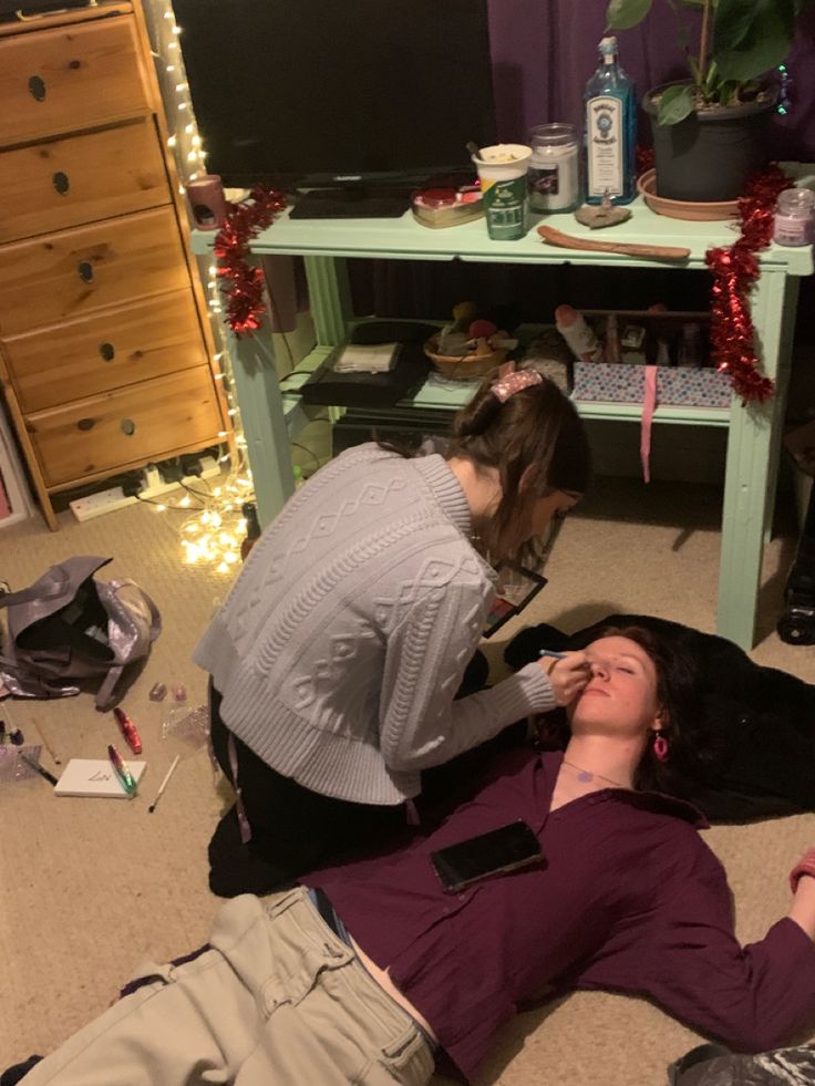 two people laying on the floor in front of a table with christmas lights and decorations