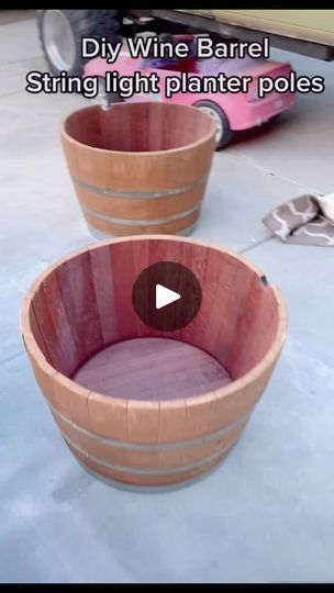 two wine barrels sitting next to each other on top of a cement floor with the words diy wine barrel string light planter poles