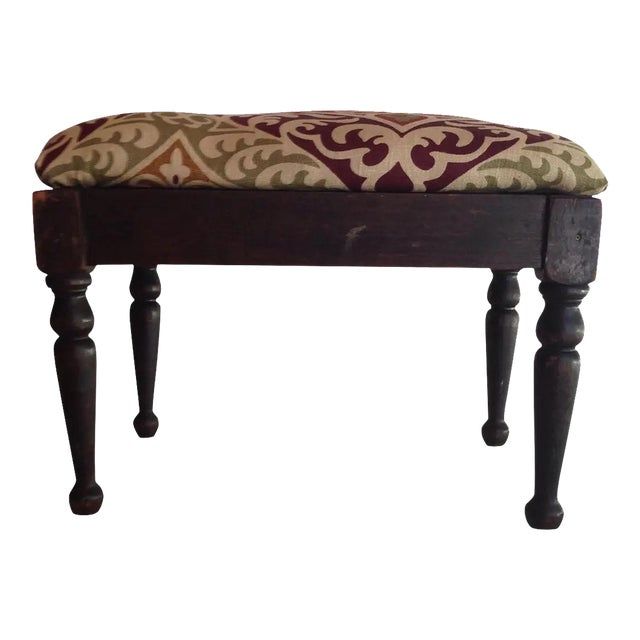 an upholstered bench with wooden legs and a patterned seat cushion on it's back