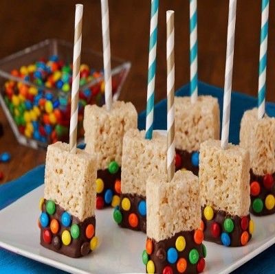 rice krispy treats are arranged on a white plate with candy and lollipops