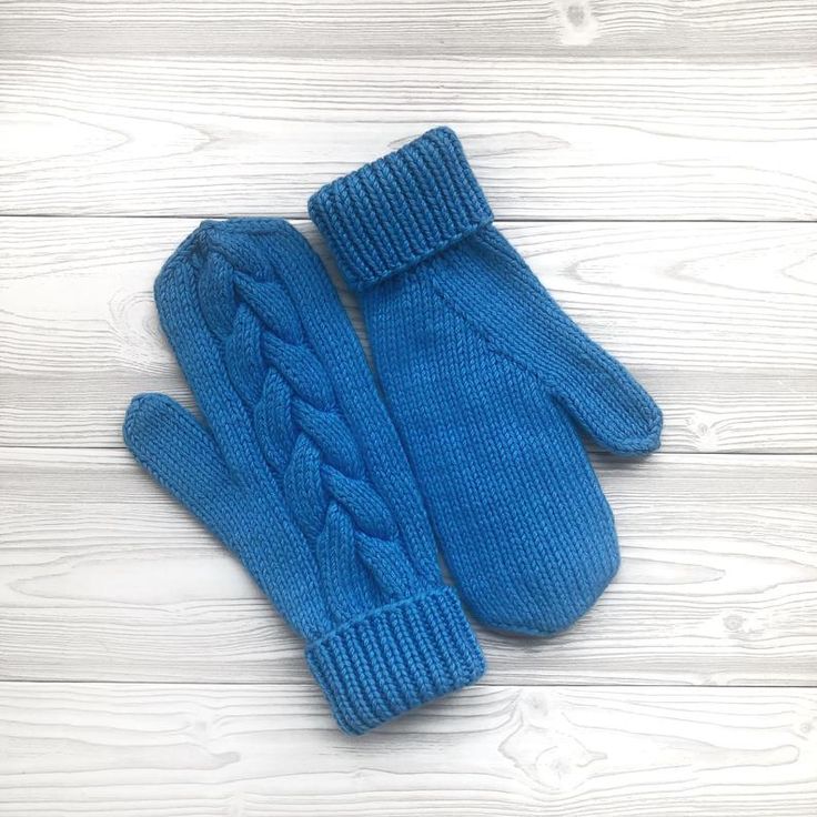 a pair of blue knitted mittens sitting on top of a white wooden floor