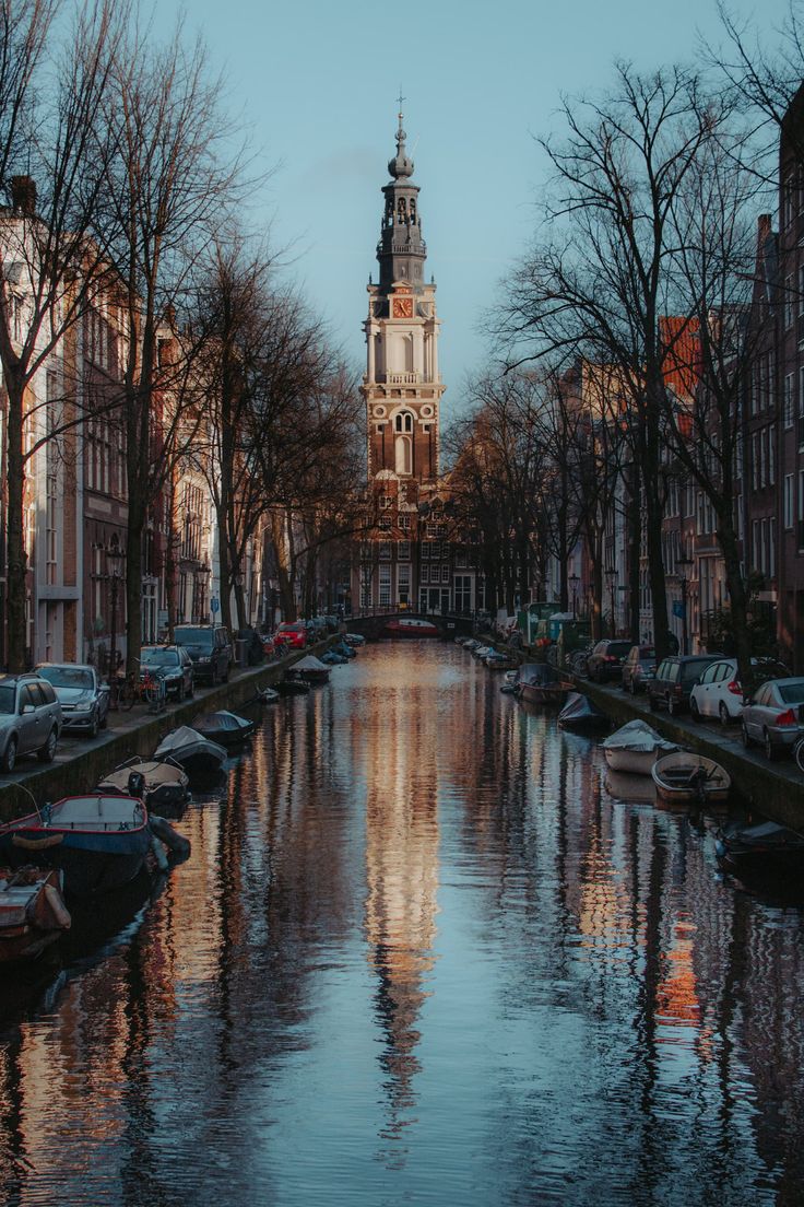 boats are lined up along the side of a canal in front of buildings and trees