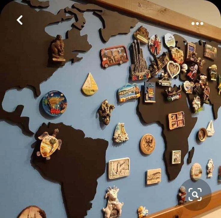 a world map made up of pins and magnets on a blue wall with a wooden frame