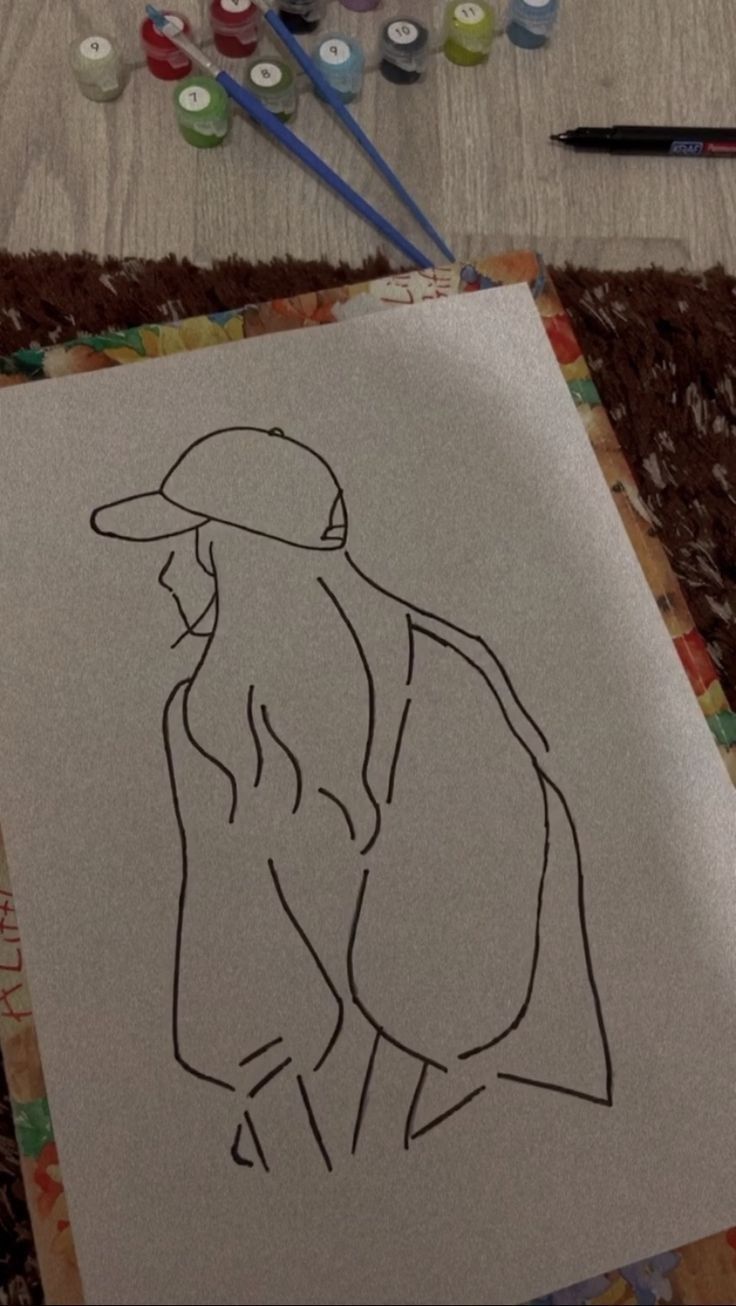 a drawing of a person with a hat on sitting next to some paintbrushes