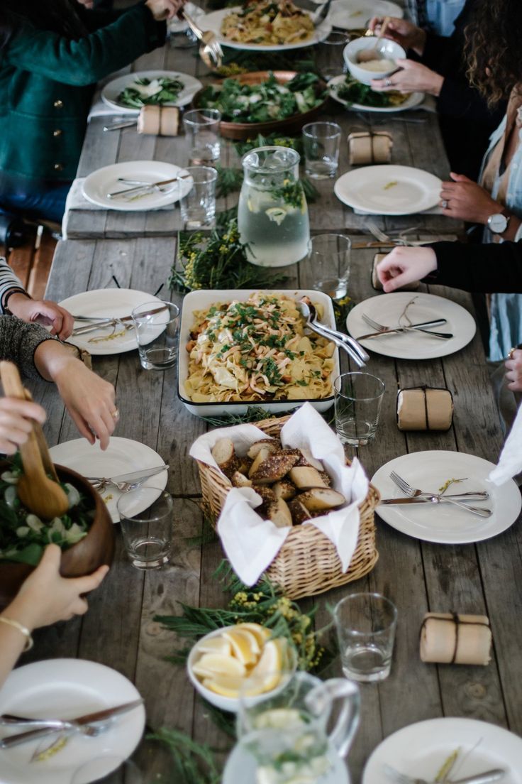 a group of people sitting at a long table with plates and bowls full of food