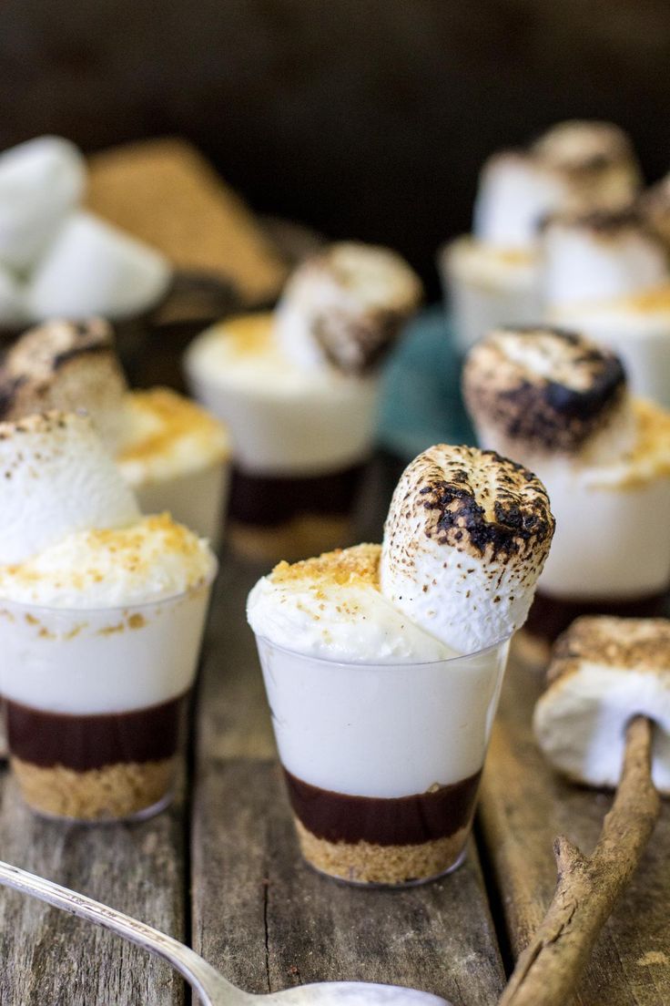 small desserts with marshmallows and chocolate are on a wooden table, ready to be eaten