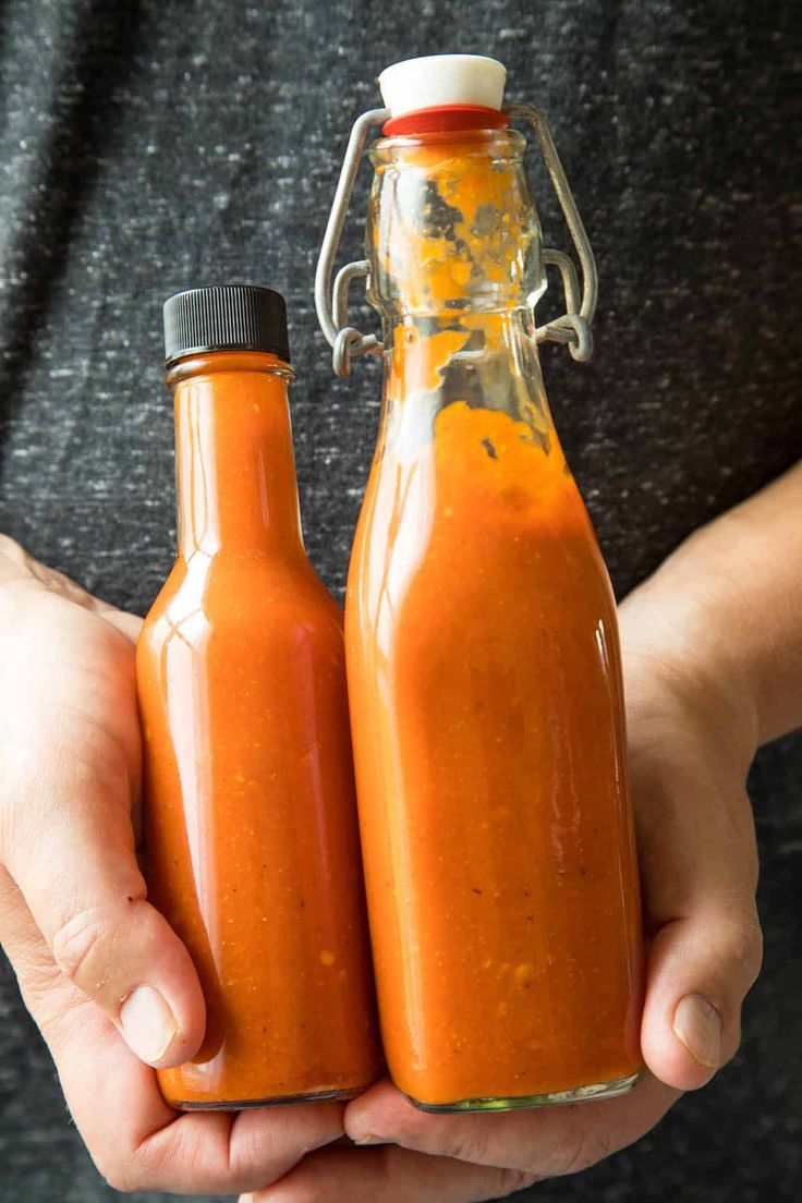 two bottles of hot sauce in their hands