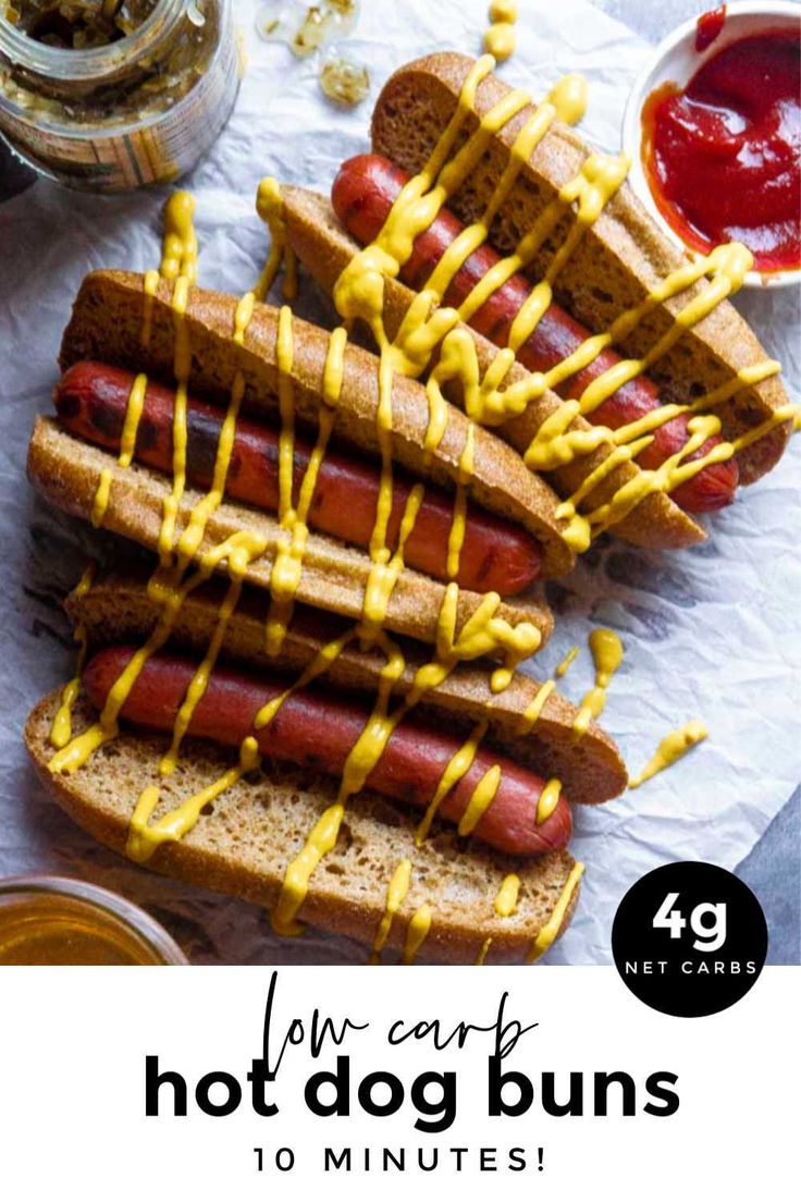 hotdogs with mustard drizzled on them and condiments next to them