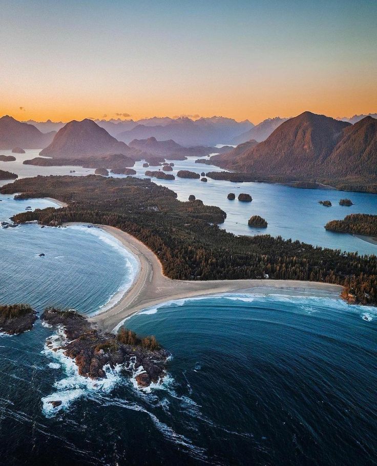 an aerial view of the ocean with mountains in the background