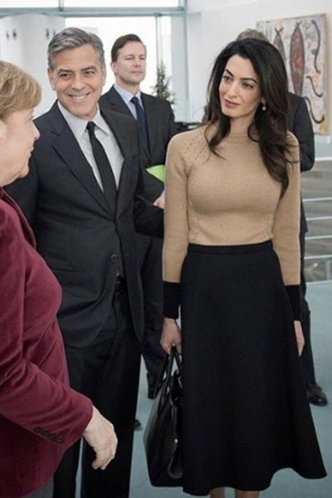 two women shaking hands with three men in suits and ties standing behind them, all looking at each other