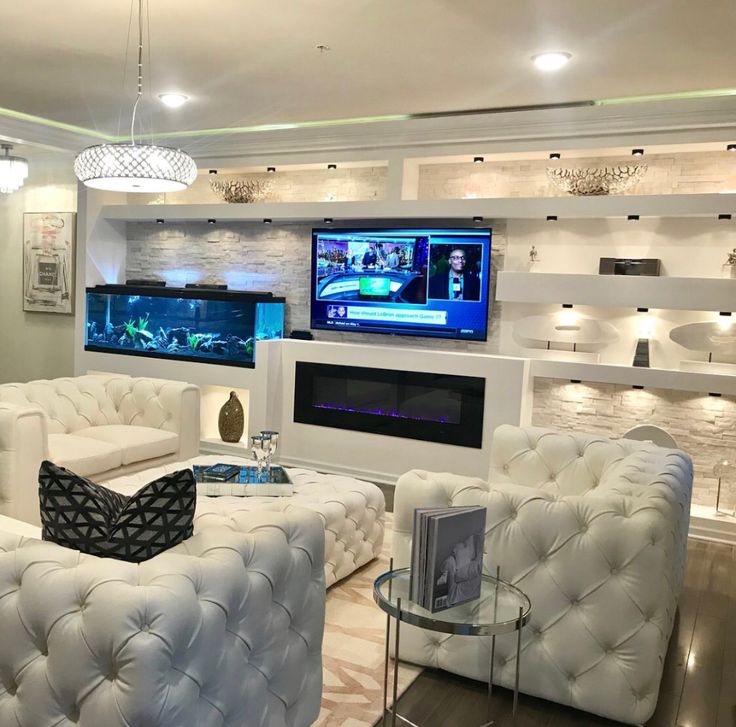 a living room filled with white furniture and a flat screen tv mounted on the wall