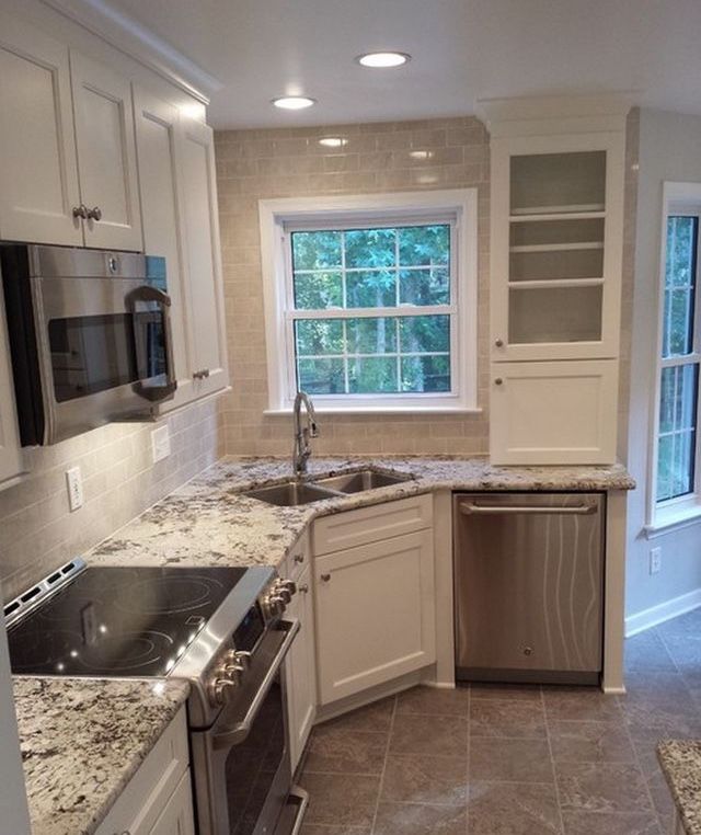 an empty kitchen with granite counter tops and white cabinets, along with stainless steel appliances