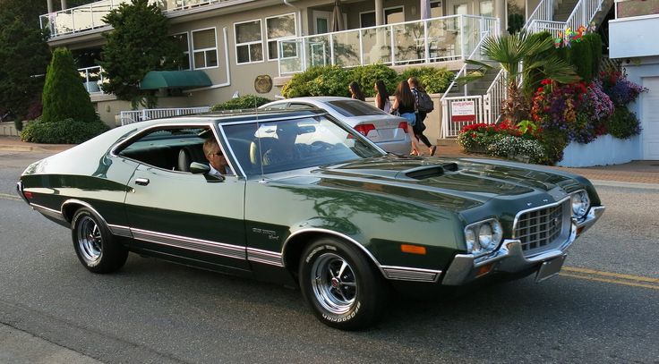 a green car is parked on the side of the road in front of an apartment building