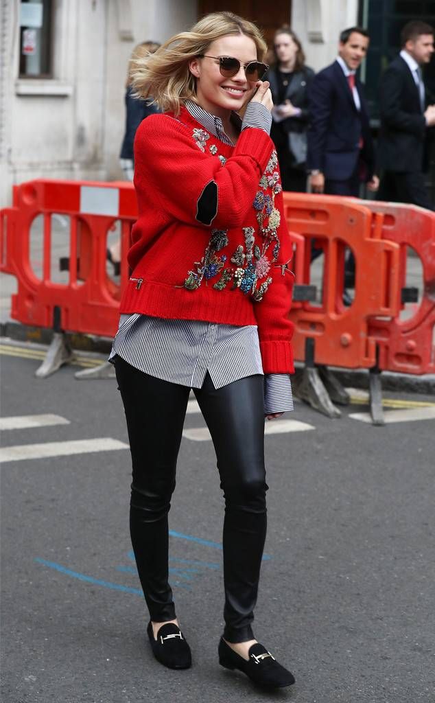 a woman in red sweater and black pants talking on cell phone