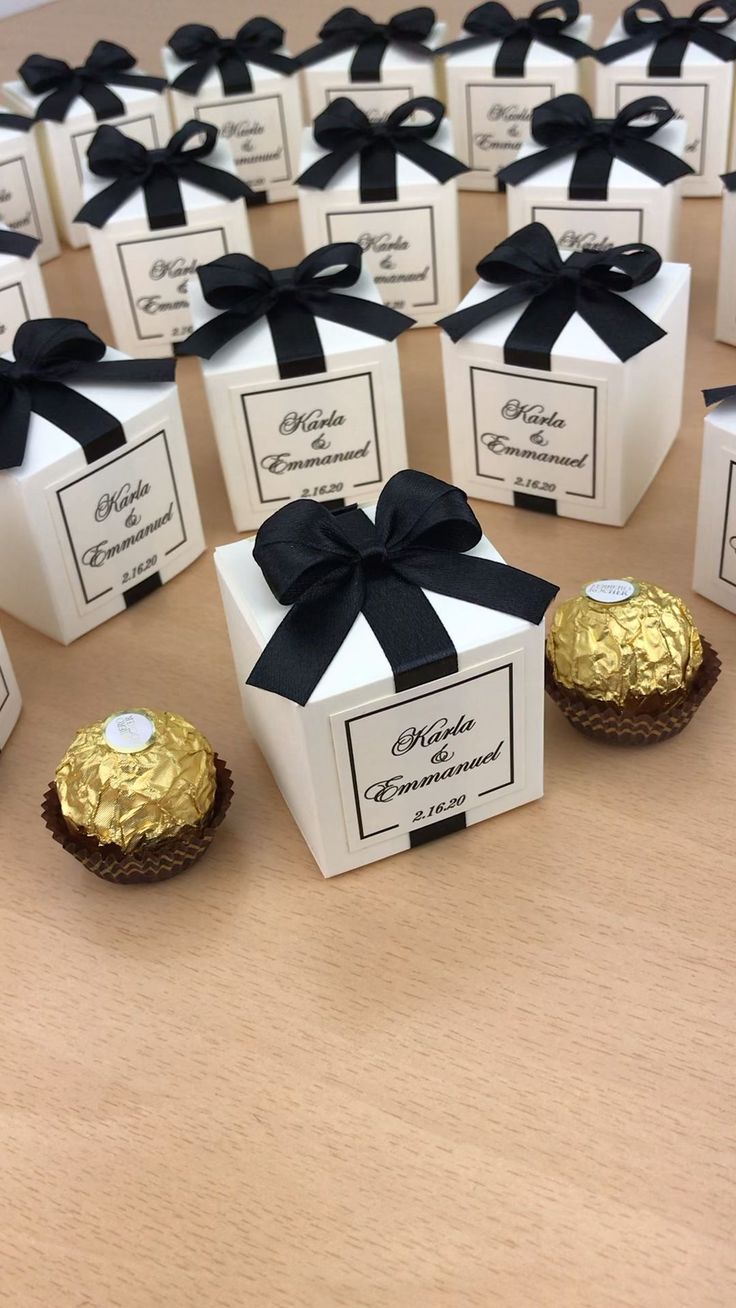 chocolates wrapped in black and white paper are arranged on a wooden table with bows