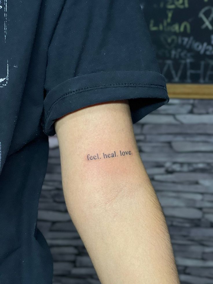 a person with a small tattoo on their arm that says tech heal love in cursive writing