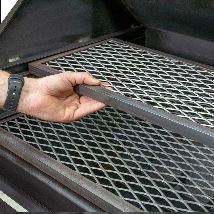 a person is holding onto the grill grate on their left hand and pulling it out