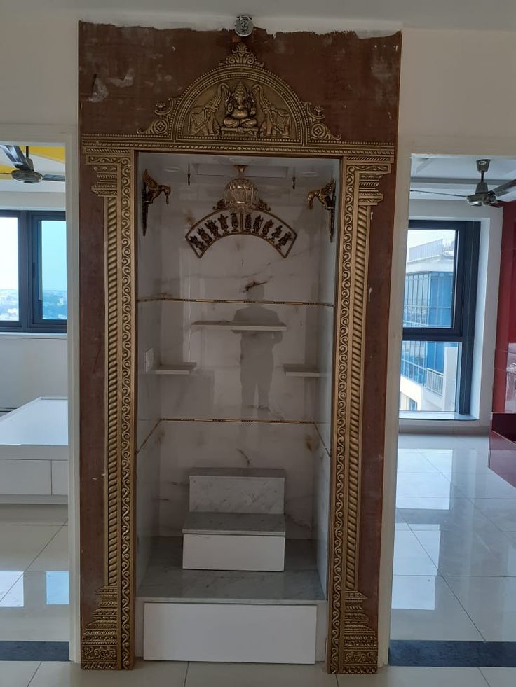 an empty room with a large gold framed mirror on the wall and marble steps leading up to it